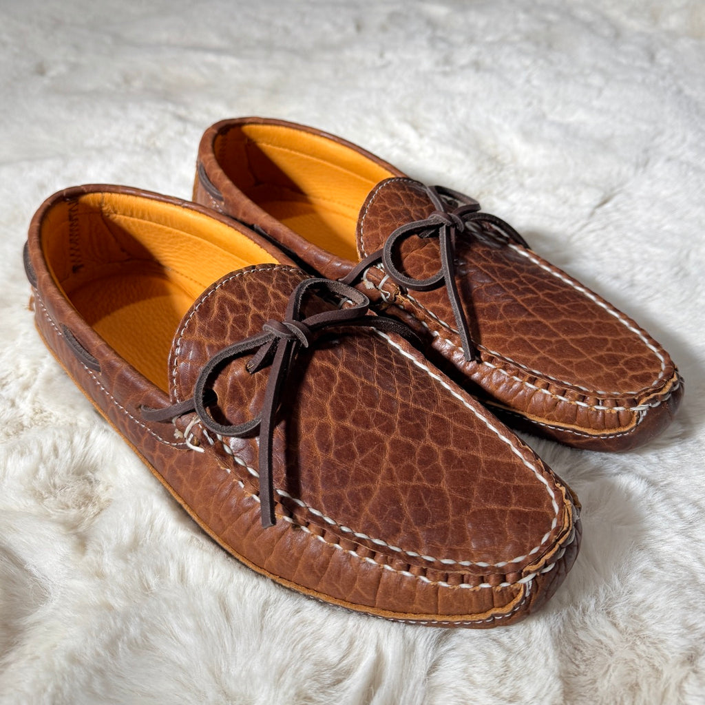Pair of brown leather moccasins on a white fur surface