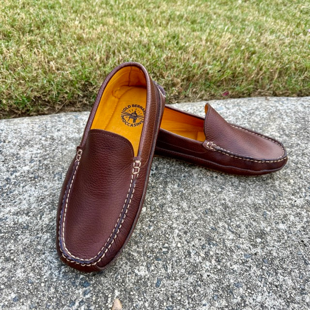 Brown leather loafers on a concrete surface with grass in the background