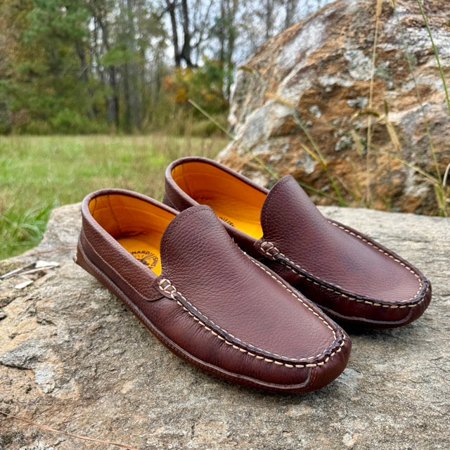 Pair of brown leather loafers on a rock with a natural background