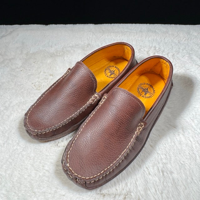 Pair of brown leather loafers on a white textured surface