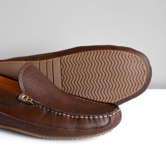 Brown leather loafer shoes with a focus on the sole on a light gray background