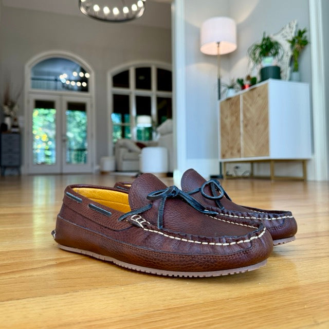 Brown leather shoes on a wooden floor with a blurred indoor background