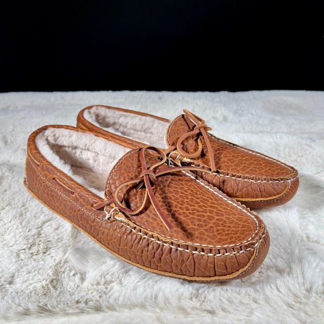 Pair of brown moccasin slippers on a white fluffy surface