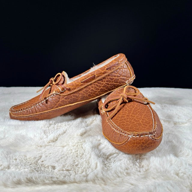 Pair of brown leather moccasins on a white surface with a black background