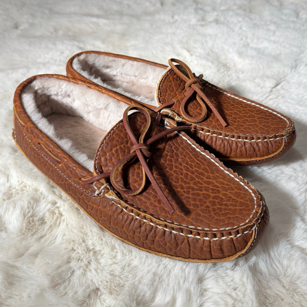 Pair of brown moccasin slippers on a white fluffy surface