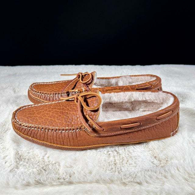 Pair of brown moccasin slippers on a white surface with a black background