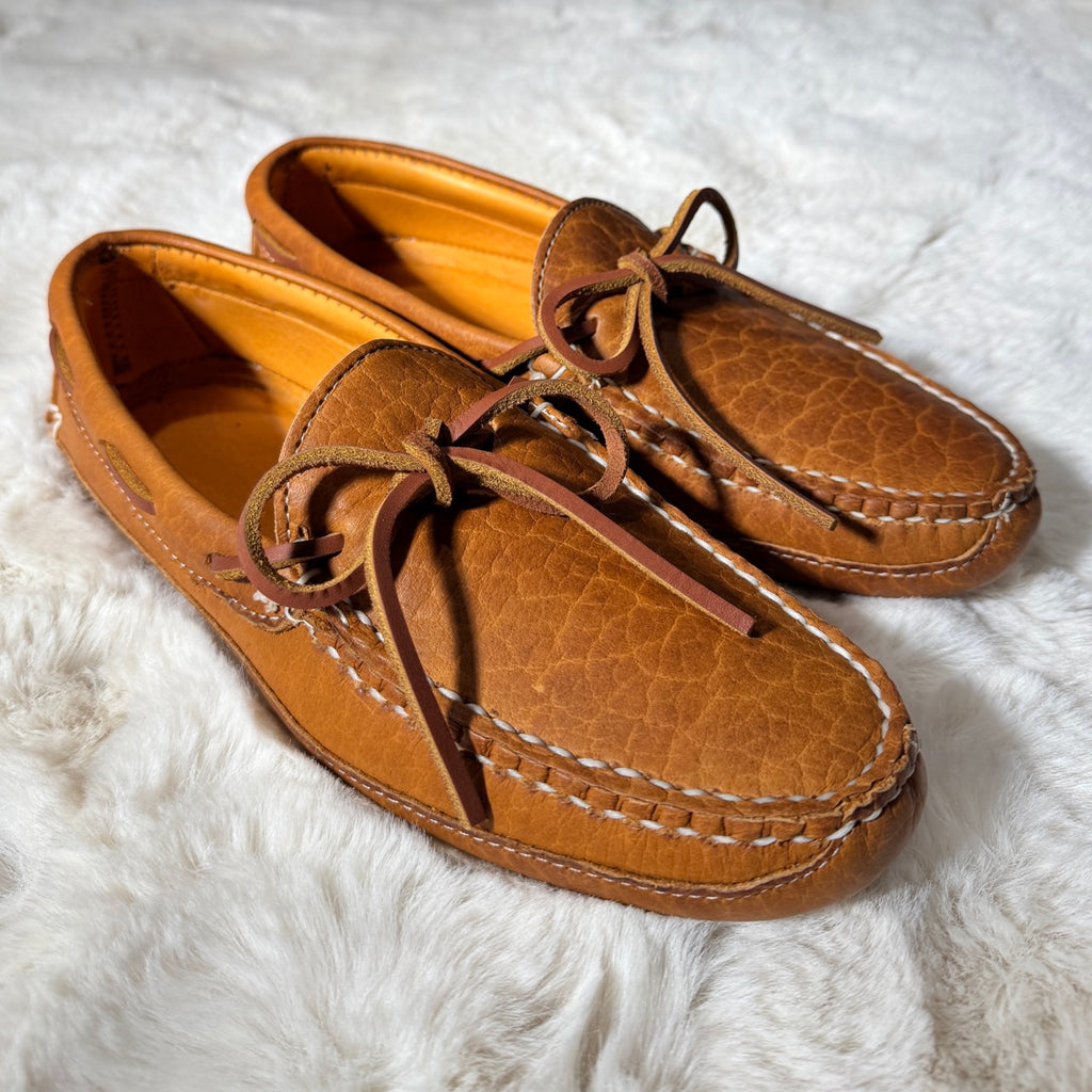 Pair of brown leather shoes with laces on a white fluffy surface