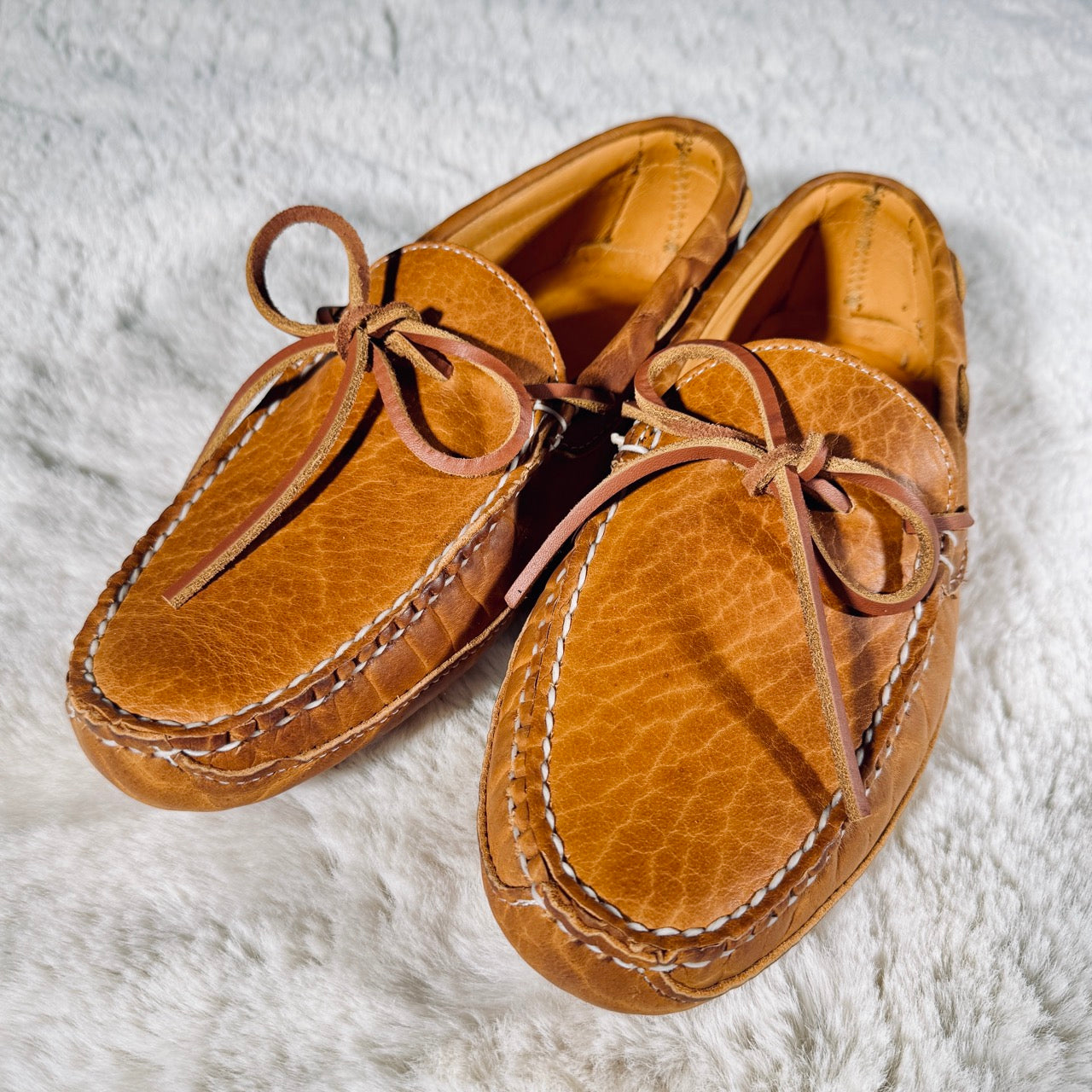 Pair of brown leather moccasins on a white fur surface