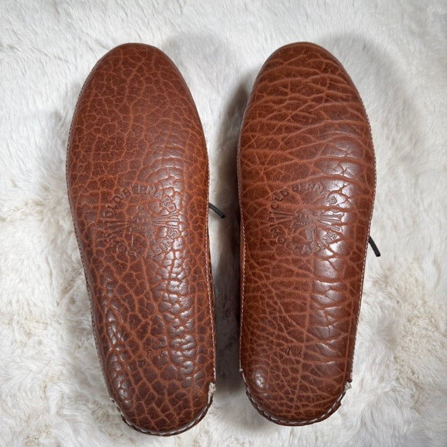 Pair of brown leather shoes with embossed design on a white textured background