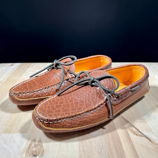 Pair of brown leather shoes with orange lining on a wooden surface
