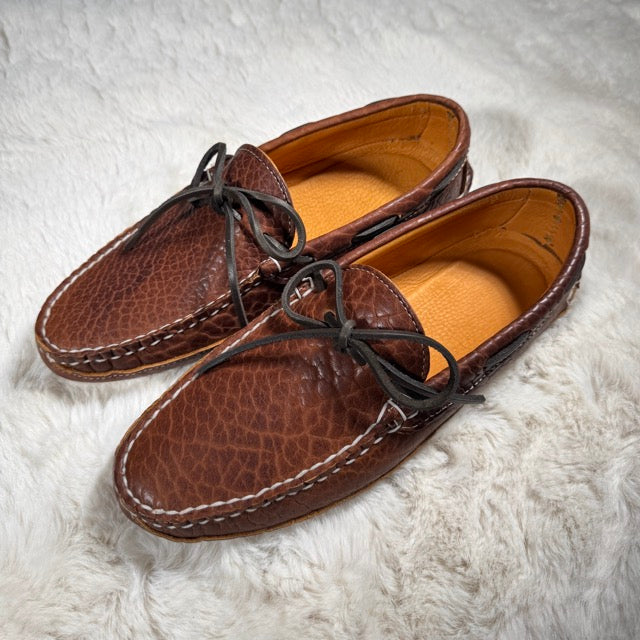 Pair of brown leather shoes on a white fur surface